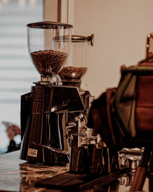 Professional coffee grinders filled with roasted beans on a café counter