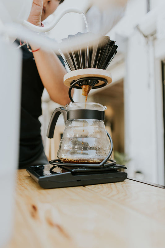 Pour-over coffee brewing in a café with a dripper and glass carafe