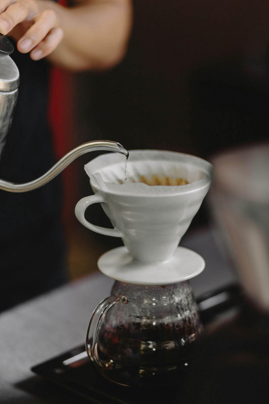 Hot water poured from a gooseneck kettle into a pour-over coffee filter, illustrating controlled brewing agitation