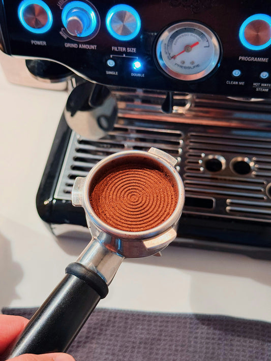 Ground coffee in an espresso portafilter before puck preparation and extraction